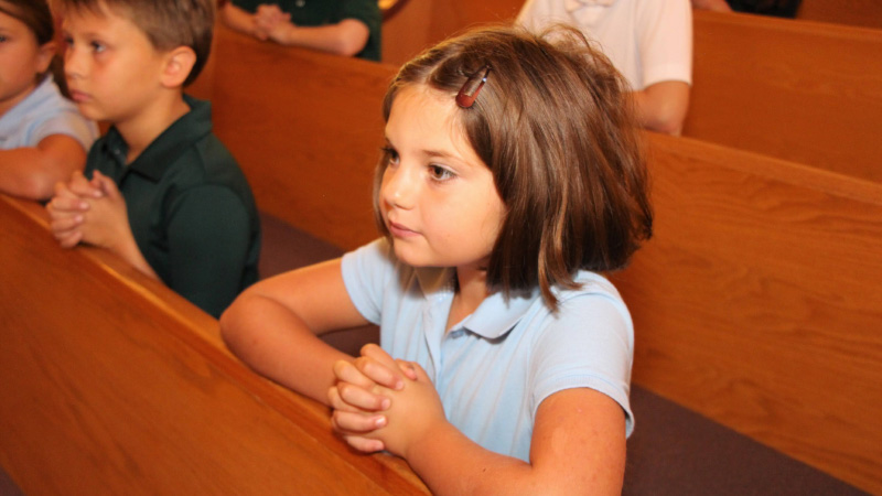 Photo of a young student kneeling at church